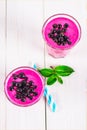 Smoothies of black currant in glass glasses with straws on a white wooden table. Top view. Royalty Free Stock Photo
