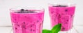 Smoothies of black currant in glass glasses with straws on a white wooden table. Royalty Free Stock Photo