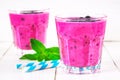 Smoothies of black currant in glass glasses with straws on a white wooden table. Royalty Free Stock Photo