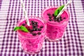 Smoothies of black currant in glass glasses with straws on a white wooden table. Royalty Free Stock Photo