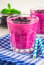 Smoothies of black currant in glass glasses with straws on a white wooden table. Royalty Free Stock Photo