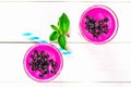 Smoothies of black currant in glass glasses with straws on a white wooden table. Top view. Royalty Free Stock Photo