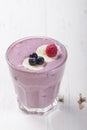 Smoothies of frozen raspberries, blueberries and banana with yogurt in a glass on a white table. Royalty Free Stock Photo