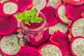 Smoothies of red organic dragon fruit and pieces of dragon fruit on an old wooden background