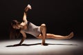 Dynamic portrait of young flexible contemp dancer dancing isolated on dark studio background in spotlight. Art, beauty