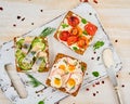 Smorrebrod - traditional Danish sandwiches. Black rye bread with herring, egg, tomatoes, radish on white wooden table, top view