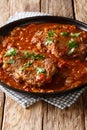 Smothered food Swiss steak in a spicy tomato sauce with vegetables close-up. vertical