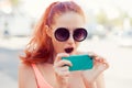 SMS. Closeup portrait funny shocked young red head girl woman looking at phone seeing surprising news photos message with Royalty Free Stock Photo