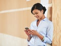 The sms that she was waiting for. a smiling young woman using her cellphone while standing in an office. Royalty Free Stock Photo