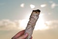 Smudging Ritual using burning thick leafy bundle of White Sage on the beach at sunrise in front of the lake