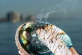 Smudging Ritual using burning thick leafy bundle of White Sage in bright polished Rainbow Abalone Shell on the beach at sunrise Royalty Free Stock Photo