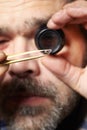 Smuggler of diamonds watching gems with eye loupe