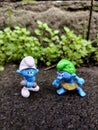 Wild Smurf and Hefty Smurf Figurines on Ground with Green Plants Royalty Free Stock Photo