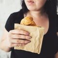 Overweight woman hesitating to eat croissant