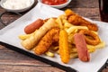 Snack plate with french fries, crispy chicken, cheese sticks, sausage and spring rolls on wooden table Royalty Free Stock Photo