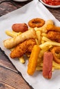 Snack plate with french fries, crispy chicken, cheese sticks, sausage and spring rolls on wooden table Royalty Free Stock Photo