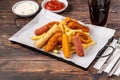 Snack plate with french fries, crispy chicken, cheese sticks, sausage and spring rolls on wooden table Royalty Free Stock Photo
