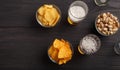 Snack in pub. Nachos, chips and pistachios in glass plates, two glasses on dark wooden table