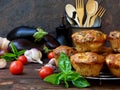 Snack savory muffins cakes with eggplant, tomatoes, basil and cheese on wooden background.