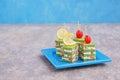 Snack, savoury spinach biscuit  sandwices or canapes layered with cream cheese and salted salmon on a blue plate against a gray Royalty Free Stock Photo