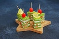 Snack, savoury spinach biscuit sandwices or canapes layered with cream cheese and salted salmon on a wooden board in the shape of Royalty Free Stock Photo