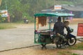 A snack vendor on a bike selling food in the rain