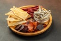 snacks for beer, Dried fish mix on wood plate. dried fish chorizo sausage meat carpaccio on a dark background. place for text, top