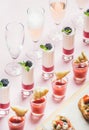 Snacks, brushetta sandwiches, gazpacho shots, desserts over pastel pink background