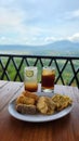 Snacks and iced drinks served with a scenic mountain view on a wooden table Royalty Free Stock Photo