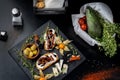 Snacks are laid out on black slate, physalis, salami, cheese and sun-dried tomatoes.