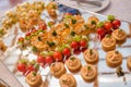 Snacks, mini sandwiches with fish and meat, decorated with cherry tomatoes and tartlets with various fillings