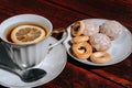 Snacks and sweets for tea in a small white saucer. Beautiful tea set. White ceramic Cup of tea with lemon on a wooden table Royalty Free Stock Photo