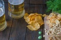 Snacks to beer, on a wooden board and two mugs of beer,on a wooden table. Chips, peanuts, pieces of fish,crackers, dill. Copy spac