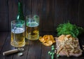 Snacks to beer, on a wooden board and two mugs of beer.Chips, peanuts, pieces of fish,crackers, dill, bottle.Copy space.