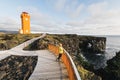 SNAEFELLSNES,Woman in yellow raincoat watching sunset at Svortuloft Lighthouse, Snaefellsnes peninsula, Iceland