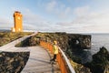 SNAEFELLSNES, ICELAND - AUGUST 2018: woman in yellow raincoat watching sunset at Svortuloft Lighthouse