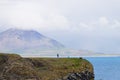 Unidentified tourists standing at the cliff near Gatklettur Stone Arch, Iceland