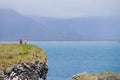 Unidentified tourists standing at the cliff near Gatklettur Stone Arch at Snaefellsnes Peninsula, Iceland