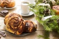 Snail chocolate muffins served with coffee on the background of a wreath of fir branches and cones. Rustic style Royalty Free Stock Photo