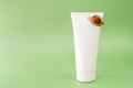 Snail cosmetic.Snails on a white tube on a green background.Organic natural cosmetics with snail slime.Cosmetic tube