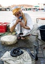 A snake charmer plays his flute towards a cobra in Djemaa el-Fna, the main square in the Marrakesh medina in Morocco. Royalty Free Stock Photo