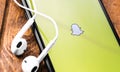 Snapchat logo on the screen Apple iPhone with Earpods