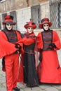 Three masked people with red costumes at the Venice Carnival