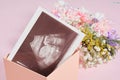 A snapshot of an ultrasound scan and flowers on a pink background pregnancy and motherhood concept, conscious parenthood