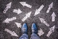 Sneaker shoes and arrows pointing in different directions on asphalt, choice concept Royalty Free Stock Photo