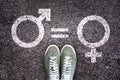 Sneaker shoes on asphalt background with gender symbols, gender equality concept
