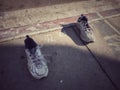 Sneaker shoes left on a sidewalk by a person with feet
