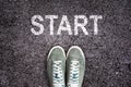 Sneaker shoes and the word START written on asphalt ground, new life
