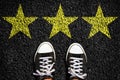 Sneakers on an asphalt road. Yellow stars. View from above. Assessment concept. Business. Lifestyle. Royalty Free Stock Photo