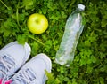 Sneakers, bottle of water and apple on fresh green grass Royalty Free Stock Photo